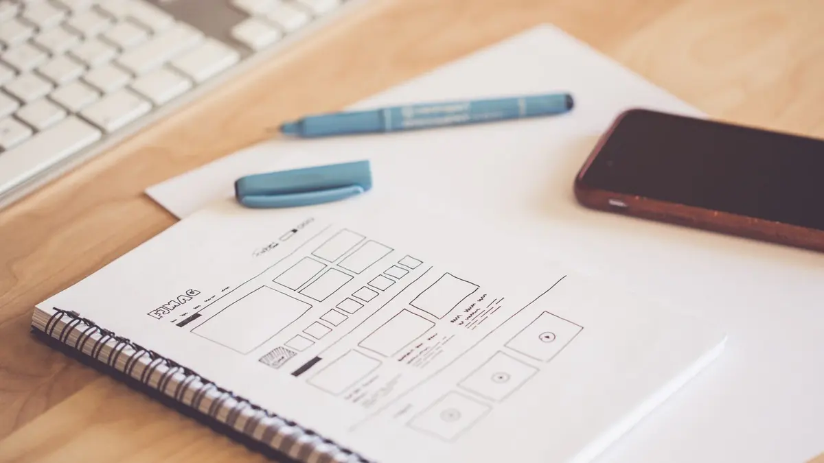 Main tenant un carnet ouvert avec une promesse commerciale entourée, bureau lumineux et notes colorées